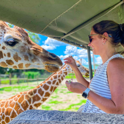 a close up of a man and a woman feeding a giraffe